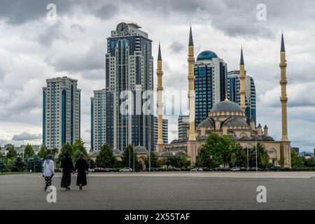 The women walk toward Grozny City skyscrapers and the 'Heart of Chechnya' mosque in the downtown of Grozny, the capital of Chechen Republic, Russia Stock Photo