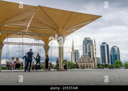 The local people on the square in downtown of Grozny, Chechen Republic, with the 'Heart of Chechnya' mosque and Grozny city skyscrapers nearby. Stock Photo