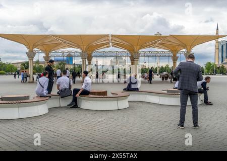 The local people on the square in downtown of Grozny, Chechen Republic, with the 'Heart of Chechnya' mosque and Grozny city skyscrapers nearby. Stock Photo