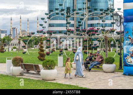 The local people in the green park close to the Grozny city skyscrapers and 'Heart of Chechnya' mosque in center of Grozny, the capital of Chechnya Stock Photo