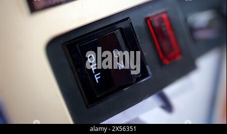 Close-up view of an analog on-off switch in the off position, with a switched-off red light Stock Photo
