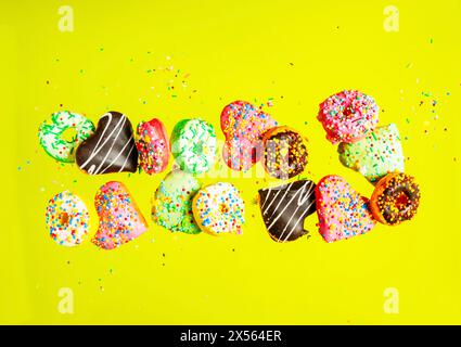 Multicolored donuts isolated on yellow background. Top view Stock Photo
