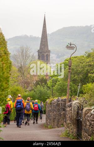 Group of walkers ramblers and hikers walking through the Derbyshire Peak District town of Bakewell towards the All Saints' parish Church, Stock Photo