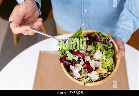 Mixed salad leaves in bamboo bowl in male's hand. Healthy eating and dieting concept. Stock Photo