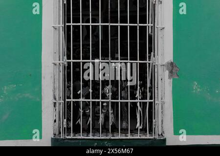245 Windowshop with white-painted, ironwork grill of a souvenir store on the jade-green chipping wall of a colonial house. Trinidad-Cuba. Stock Photo