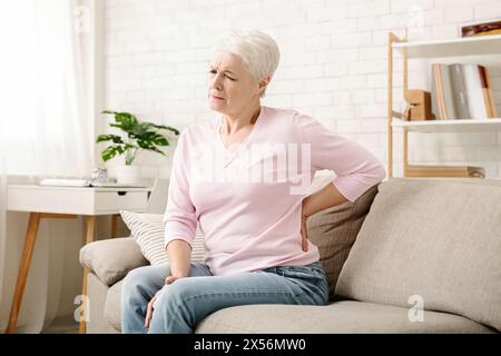 Senior woman suffering from backache at home Stock Photo
