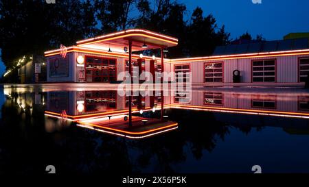 Old beautiful illuminated petrol station on a rainy night with a reflection in a puddle Stock Photo