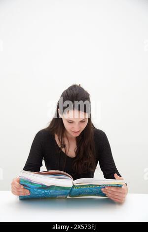 Young woman looking at exhibition catalog. David Hockney, ¥A Bigger Picture¥ exhibition, Guggenheim Museum, Bilbao, Biscay, Basque Country, Spain Stock Photo