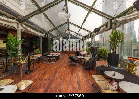 Beautiful interior view of a rooftop restaurant in Manhattan featuring a transparent ceiling, contemporary furniture. New York. USA. Stock Photo