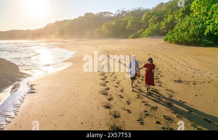 Two tourists walking on the sandy beach, Playa Cocalito, Puntarenas, Costa Rica Stock Photo
