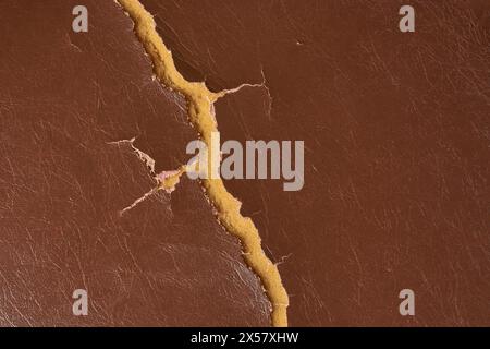 brown color used worn and torn leather seat surface, repair and services of damaged upholstery restoration concept, close-up in full frame background Stock Photo