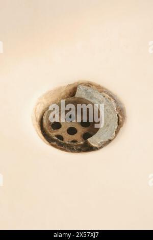 old broken and dirty bathroom sink drain mesh hole close-up, rusty limescale bath or tub drainage, cleaning repairing bathroom equipment concept Stock Photo