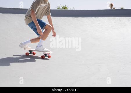 A young man is skateboarding down a cement ramp with a surfskate, showcasing his skill and balance in an urban skate park setting. Stock Photo
