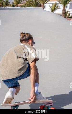 Captured in motion, a young man with a casual style is skillfully handling a surfskate at a skatepark. His concentration and physical coordination are Stock Photo