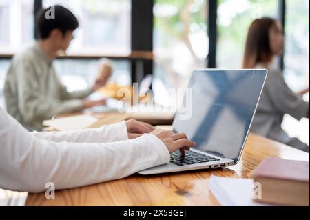 A close-up image of a college student using her laptop computer in the classroom or co-working space. education concept Stock Photo