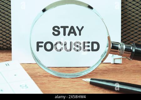 Concept words Stay focused written through a magnifying glass on a white sheet Stock Photo