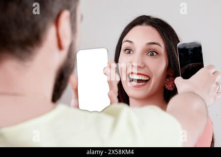 Energetic sharing of digital content between man and woman, using smartphone visuals to communicate instead of words Stock Photo