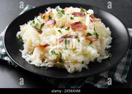 Slovak potato dumplings halusky with steamed sauerkraut and bacon on black background Stock Photo