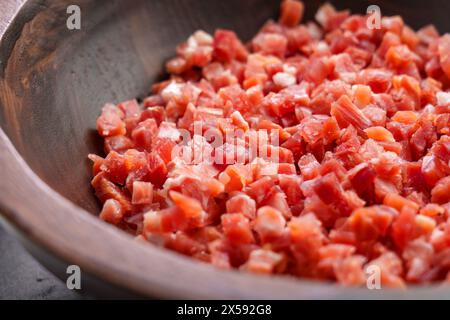 Traditional Spanish jamon cubes in wooden bowl close up. Meat cooking ingredient. Stock Photo