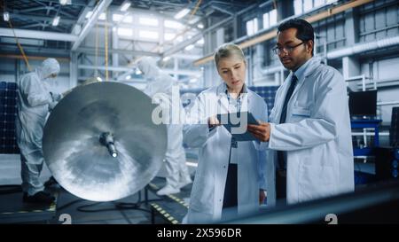 Team of Engineers Working on Satellite Construction, Use Tablet Computer Talk about Data. Aerospace Spaceship Manufacturing Facility: Team of Scientists Building Spacecraft for Space Exploration Stock Photo