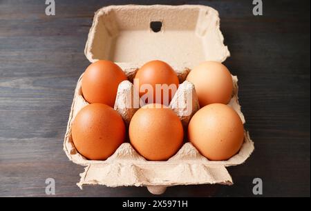 Organic Chicken Eggs in Paper Carton Box Isolated on Black Wooden Table Stock Photo