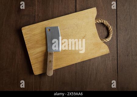 A mini meat cleaver knife on wooden cutting board with ropes Stock Photo