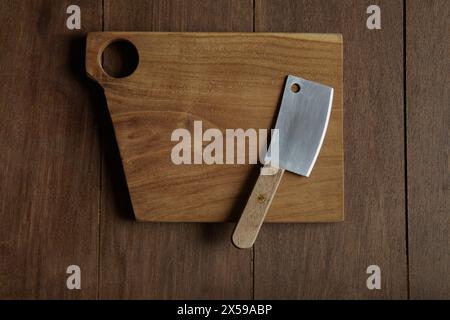 A small meat cleaver knife on wooden cutting board with holes Stock Photo