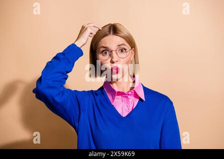 Photo of young blonde bob hair business lady pouted lips worried scratching head when had serious task isolated on beige color background Stock Photo