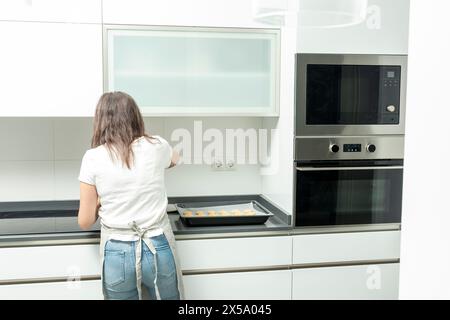 white kitchen, preparing food on countertop, built-in ovens, frosted glass cabinet, contemporary design Stock Photo