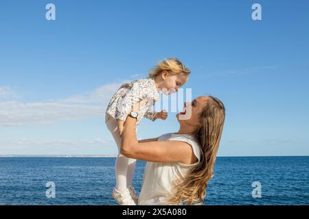 Mother and daughter portrait playing outdoor on blue sky background Stock Photo