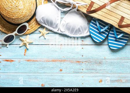 Top view of beach bag, straw hat, sunglasses, flip flops and bikini with copy space for text on a background of wooden boards. Summer holiday concept Stock Photo