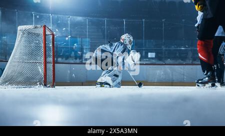 Ice Hockey Rink Arena: Goalie is Ready to Defend Score against Forward Player who Shoots Puck with Stick. Forwarder against Goaltender. Tension Moment in Sport Full of Emotions. Stock Photo