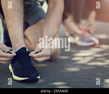 Fitness, people and tie shoes ready for workout, exercise and training for physical strength. Runners, sneakers and hands fixing laces on ground, road Stock Photo