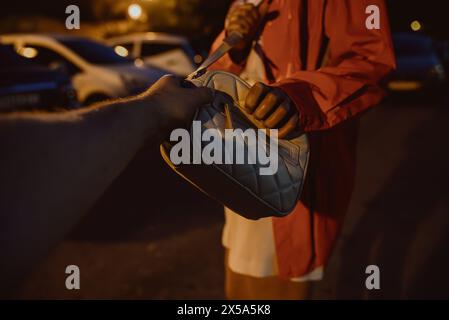 A thief robs a girl in a parking lot. Stock Photo