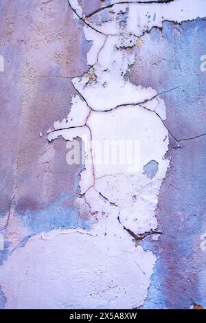 Close-up view of a weathered wall with peeling paint and visible cracks. Stock Photo