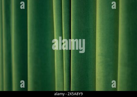 This image captures the luxurious texture of velvet curtains in a green hue, creating a soothing and elegant abstract background. Stock Photo