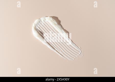 A high-resolution image showcasing the detailed texture of a white cream swiped against a soft neutral backdrop, ideal for beauty and skincare Stock Photo
