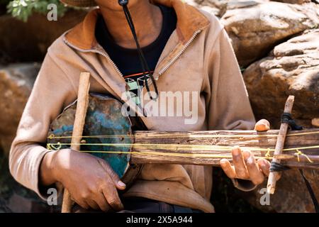 Close-up of a cropped unrecognizable African musician's hands playing a homemade stringed instrument, showcasing cultural music. Stock Photo