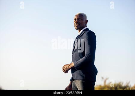 An elegant African American male model in a suit posing on a beach, looking contemplatively into the distance Stock Photo