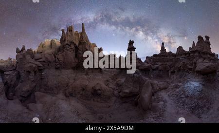 Panoramic night view of Goblin Valley State Park in Utah, USA, with hoodoo rock formations under a dazzling Milky Way. Stock Photo