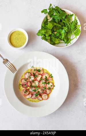 From above freshly roasted radishes served on a white plate with green tahini sauce, photographed from above. Stock Photo