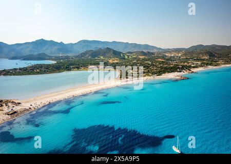 Captivating aerial shot showcasing the pristine beaches and crystal-clear waters of the Porto Giunco Beach, with a solitary yacht floating on the tran Stock Photo