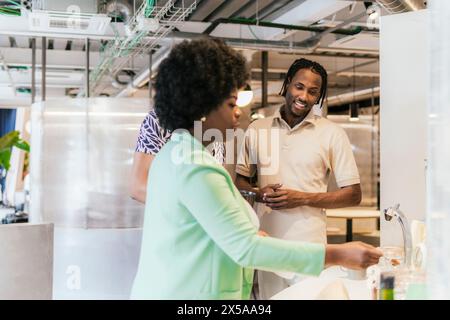 Two professionals engage in conversation at a sink in the bright, collaborative environment of a shared workspace Stock Photo