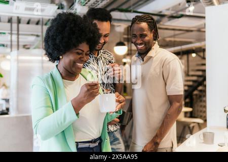 Three colleagues sharing a light moment in a modern coworking space Stock Photo