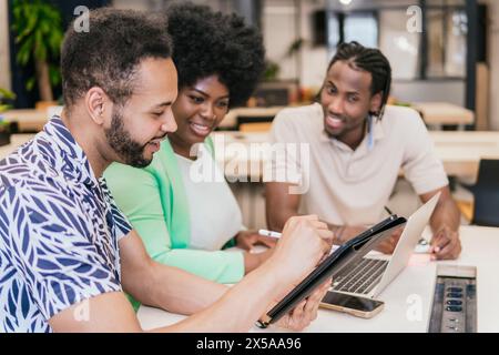 Three professionals engaged in a collaborative work session in a modern coworking space Stock Photo