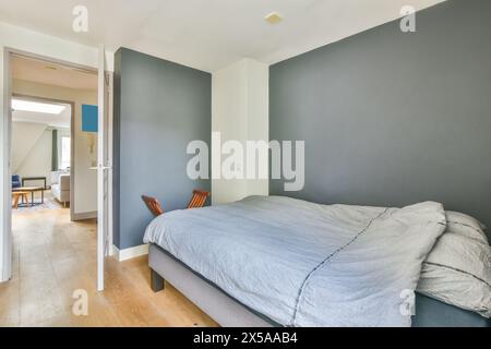 A contemporary bedroom featuring a gray palette, wooden floor, and minimal decor, creating a serene interior space. Stock Photo