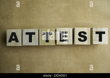 Concept of The wooden Cubes with the word Attest on wooden background. Stock Photo