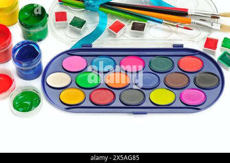 Watercolor paints, gouaches and brushes isolated on white background. Free space for text. Stock Photo