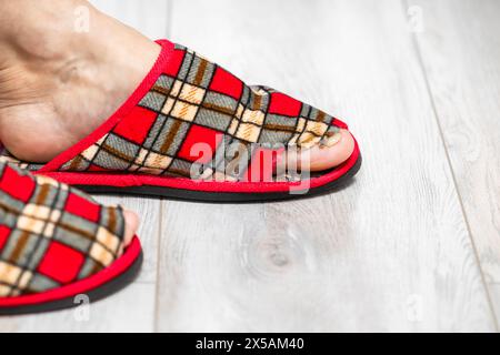 man in old slippers. old slipper. holey sneaker. the toe sticks out of the shoe in the slipper. Stock Photo