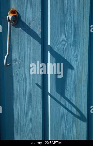 Norfolk,England, April 30th 2024, Close up shot of blue painted timber panels on a beach hut with a metal hook affixed Stock Photo